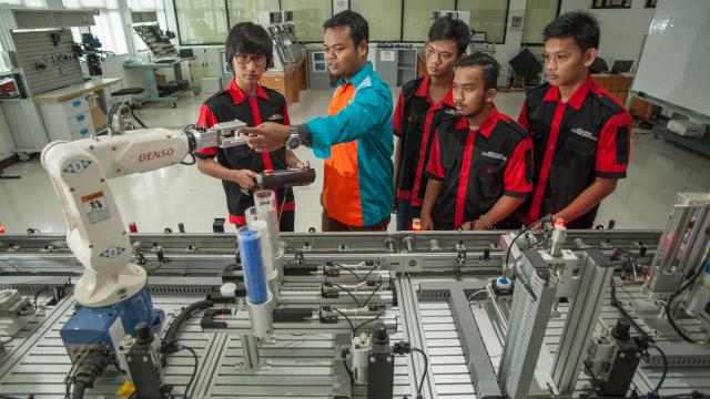 Students learn how robotic arms assist in mass production at a school in Indonesia