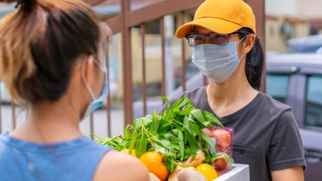 A woman delivers groceries to a homeowner while on lockdown.