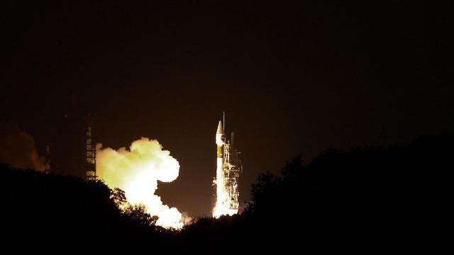 A shuttle carrying a satellite is poised for takeoff