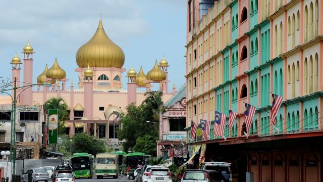 Kuching City Mosque with the colourful Saujana Building in the foreground on the right.