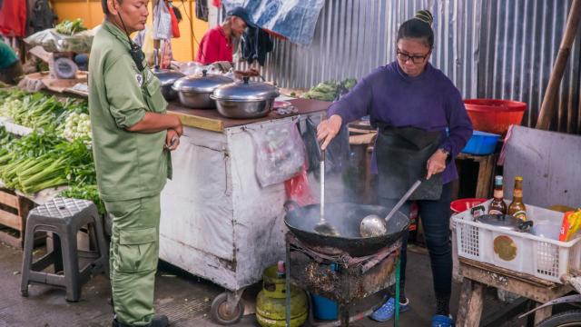 A man waits for a his order to be prepared at a food stall in Indonesia.